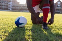 Unterteil eines männlichen Rugby-Spielers, der seine Schnürsenkel im Stadion bindet — Stockfoto