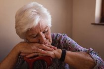 Frontansicht einer aktiven Seniorin, die zu Hause in der Küche schläft und sich auf einen Stock stützt — Stockfoto