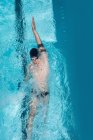 Hochwinkelblick auf junge kaukasische Schwimmer, die an sonnigen Tagen im Freibad Rückenschwimmen — Stockfoto