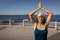 Frontansicht einer aktiven Seniorin beim Yoga auf einer Promenade unter der Sonne — Stockfoto