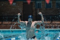 Vorderansicht junger kaukasischer Schwimmer mit erhobenen Armen feiert Sieg im Freibad in der Sonne — Stockfoto