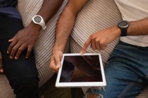 Высокоугольный вид на друзей-мужчин из разных этнических групп с помощью цифрового планшета дома — стоковое фото