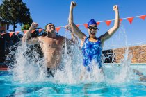Vista frontal de nadadores masculinos e femininos animados comemorando sua vitória na piscina em um dia ensolarado — Fotografia de Stock