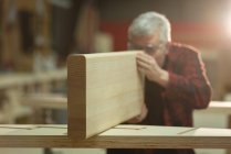 Vista frontal del carpintero tomando medidas de madera en el taller - foto de stock