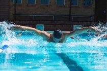 Front view of a male swimmer with swim goggle swimming the butterfly at the swimming pool — Stock Photo