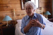 Vue de face d'une femme âgée active souffrant de douleurs thoraciques dans la chambre à coucher à la maison — Photo de stock