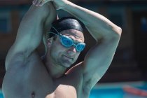 Vista de perto de um jovem nadador do sexo masculino com óculos de natação esticados na piscina — Fotografia de Stock