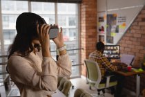 Вид збоку бізнес-леді, використовуючи гарнітуру віртуальної реальності в офісі — стокове фото