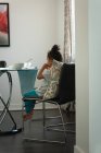 Vue arrière de la race mixte fille réfléchie assis triste à la maison tout en prenant le petit déjeuner à la maison — Photo de stock