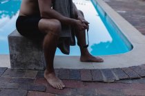 Низький розділ чоловічого плавця, що сидить на стартовому блоці біля басейну — стокове фото