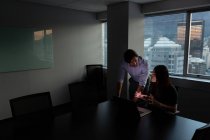 Vista frontal de jóvenes ejecutivos enfocados trabajando y discutiendo en una oficina moderna - foto de stock