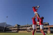 Low angle view of a male rugby players catching the ball in the air during the touch in the stadium on a sunny day — Stock Photo