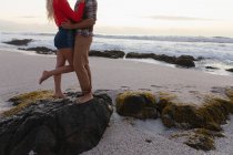 Section basse de jeune couple debout dans l'humeur romantique à la plage. Ils s'embrassent. — Photo de stock