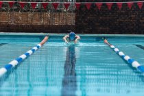 Фронтальний вид молодих кавказьких чоловіків плавець починаючи плавати інсульту метелик у відкритому плавальному басейні сонячний день — стокове фото
