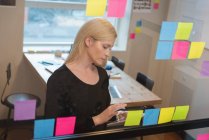 Vista frontal de empresária caucasiana trabalhando sobre tablet digital em conferência de escritório — Fotografia de Stock