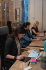 Vista laterale di donna d'affari ben vestita che utilizza tablet grafico mentre guarda campione di colore con i colleghi che lavorano duramente in ufficio — Foto stock