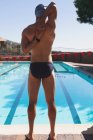Задній вид молодих кавказьких чоловіків плавець розтягування зброї під час носіння Купальники біля відкритого плавального басейну сонячний день — стокове фото
