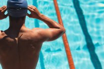 Rear view of young male Caucasian swimmer wearing swim goggle at outdoor swimming pool in the sunshine — Stock Photo