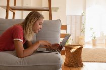 Vista laterale della donna che utilizza il computer portatile in soggiorno a casa — Foto stock
