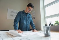 Low angle view of diverse businessman standing and working over blueprint at office conference — Stock Photo