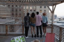Vista posteriore di diversi amici in piedi insieme in balcone a casa — Foto stock