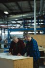 Vista frontal de carpinteros masculinos discutiendo y midiendo en taller - foto de stock