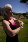 Вид збоку активних старшим жінки здійснює йога і приєднання до неї руки в парку на сонячний день — стокове фото
