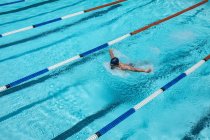 Hochwinkelblick auf junge kaukasische Schwimmer mitten im Schwimmen Schmetterlingsschlag im Freibad an sonnigen Tag — Stockfoto