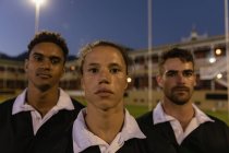 Retrato de jugadores de rugby multiétnicos masculinos de pie en el estadio y mirando a la cámara - foto de stock