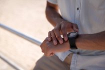 Seção média do homem usando relógio inteligente na praia — Fotografia de Stock
