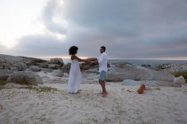 Vista lateral de pareja afroamericana bailando y disfrutando cerca del mar - foto de stock