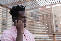 Vue latérale de l'homme afro-américain parlant sur téléphone portable dans le balcon à la maison — Photo de stock