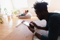 Seitenansicht eines afrikanisch-amerikanischen Mannes, der zu Hause ein digitales Tablet benutzt. er legt sich auf den Bauch — Stockfoto