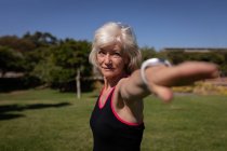 Вид сбоку активной пожилой женщины, тренирующейся в парке в солнечный день — стоковое фото