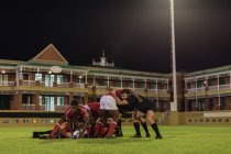 Vista laterale dei giocatori di rugby multietnici che giocano a rugby nello stadio la sera — Foto stock