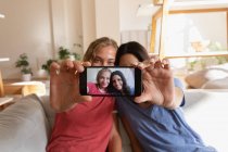 Visão frontal de mulheres tomando selfie em casa na sala de estar — Fotografia de Stock
