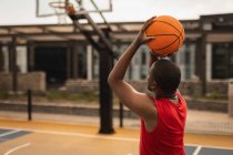 Vista trasera del jugador de baloncesto afroamericano que juega baloncesto en la cancha de baloncesto - foto de stock