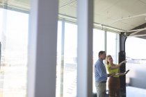 Vista lateral de maduros caucásicos hombres y caucásicos rubias mujeres arquitectos interactuando entre sí en la oficina moderna - foto de stock