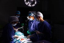 Vista lateral dos cirurgiões concentrados realizando operação no centro cirúrgico do hospital — Fotografia de Stock