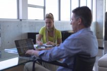 Behinderte kaukasische männliche und kaukasische weibliche Führungskräfte interagieren im Büro miteinander — Stockfoto