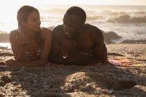 Vista frontale della giovane coppia multietnica che interagisce tra loro in spiaggia in una giornata di sole — Foto stock