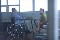 Visão lateral de deficientes maduros caucasiano masculino e caucasiano loira executiva interagindo uns com os outros no escritório — Fotografia de Stock