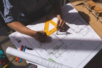 Vista de alto ângulo do arquiteto masculino trabalhando no projeto ao usar a bússola da geometria na mesa em um escritório moderno — Fotografia de Stock