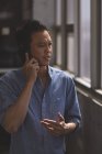 Vue de face du jeune dirigeant asiatique parlant sur un téléphone portable dans le bureau — Photo de stock