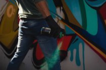 Vista trasera de la joven artista de graffiti caucásico pintura en aerosol en la pared envejecida - foto de stock