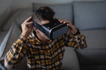 Hochwinkel-Ansicht eines jungen kaukasischen Mannes mit Virtual-Reality-Headset auf dem heimischen Sofa sitzend — Stockfoto