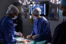 Vista lateral dos cirurgiões concentrados realizando operação no centro cirúrgico do hospital — Fotografia de Stock