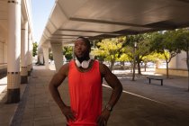 Фронтальний вид молодих афро-американських fit людина з гарнітури стоячи на тротуар під мостом — стокове фото