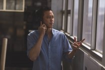 Vista frontale dell'architetto asiatico di sesso maschile che parla sul cellulare in un ufficio moderno — Foto stock