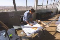 Висока кут зору чоловічого азіатських архітектора, стоячи реєстрації та працює над концепцією в сучасні офісні — стокове фото